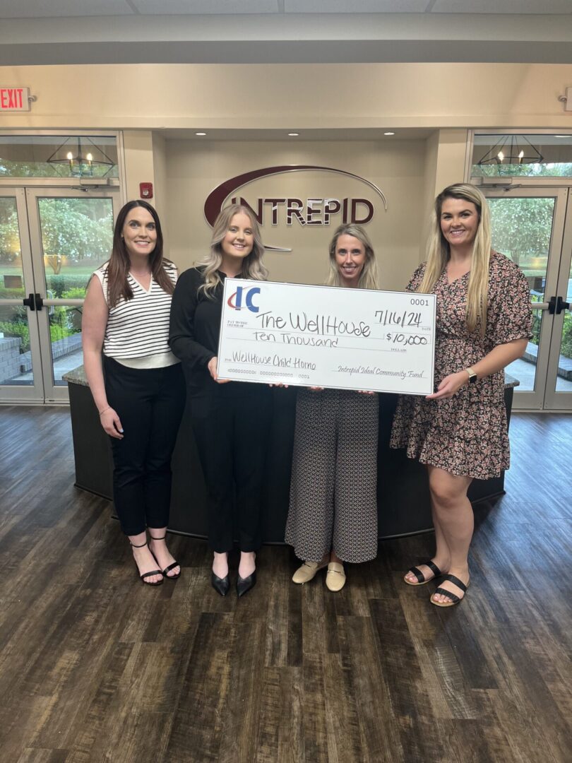 Three women holding a donation check for The WellHouse.